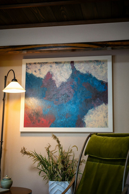 Abstract art hangs above a green chair.