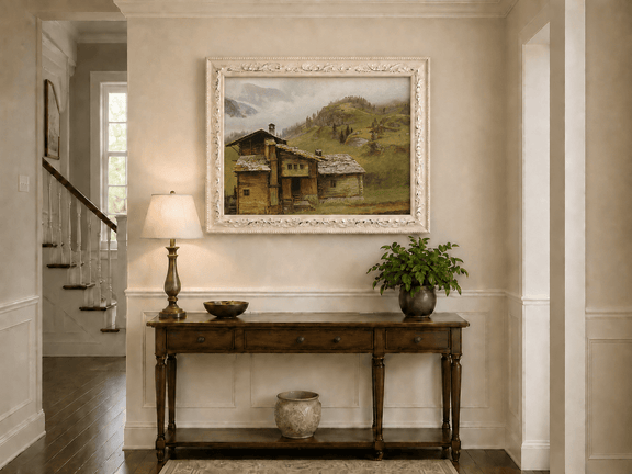 Framed hand-painted alpine landscape oil painting with a chalet, pasture and bell tower displayed above an entryway console table.