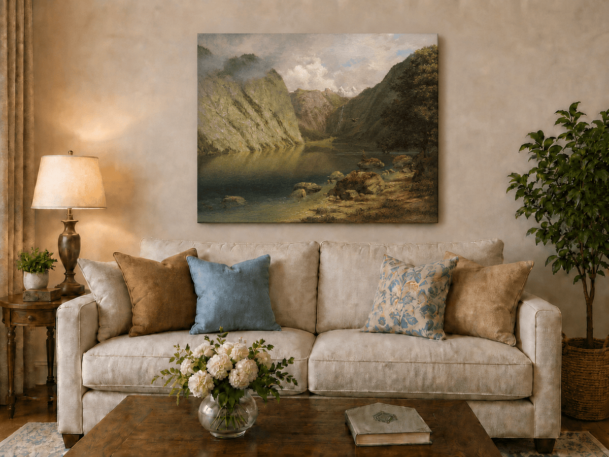 Unframed hand-painted alpine lake valley oil painting with a waterfall and rugged mountains displayed above a neutral living room sofa.