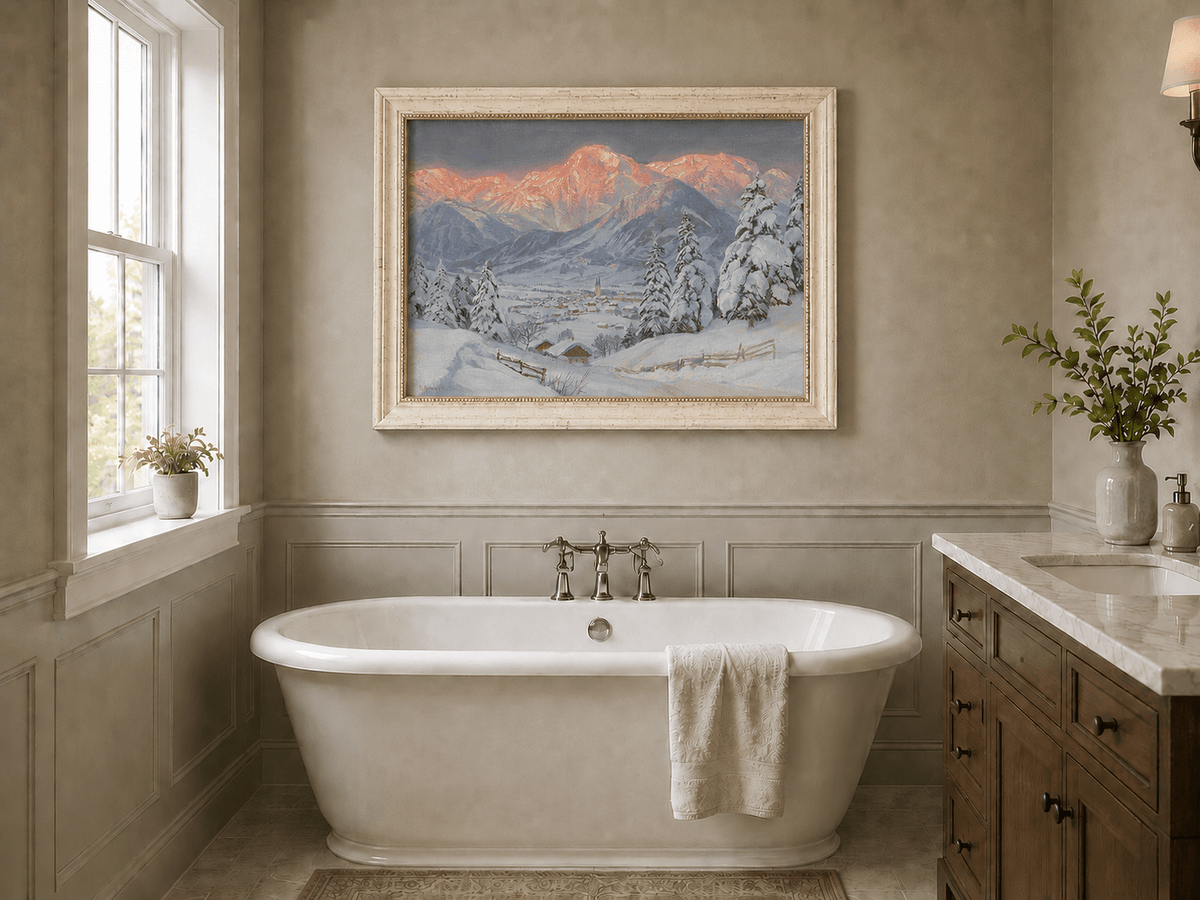 Framed hand-painted alpine town oil painting beneath glowing pink mountain peaks displayed above a freestanding bathtub.