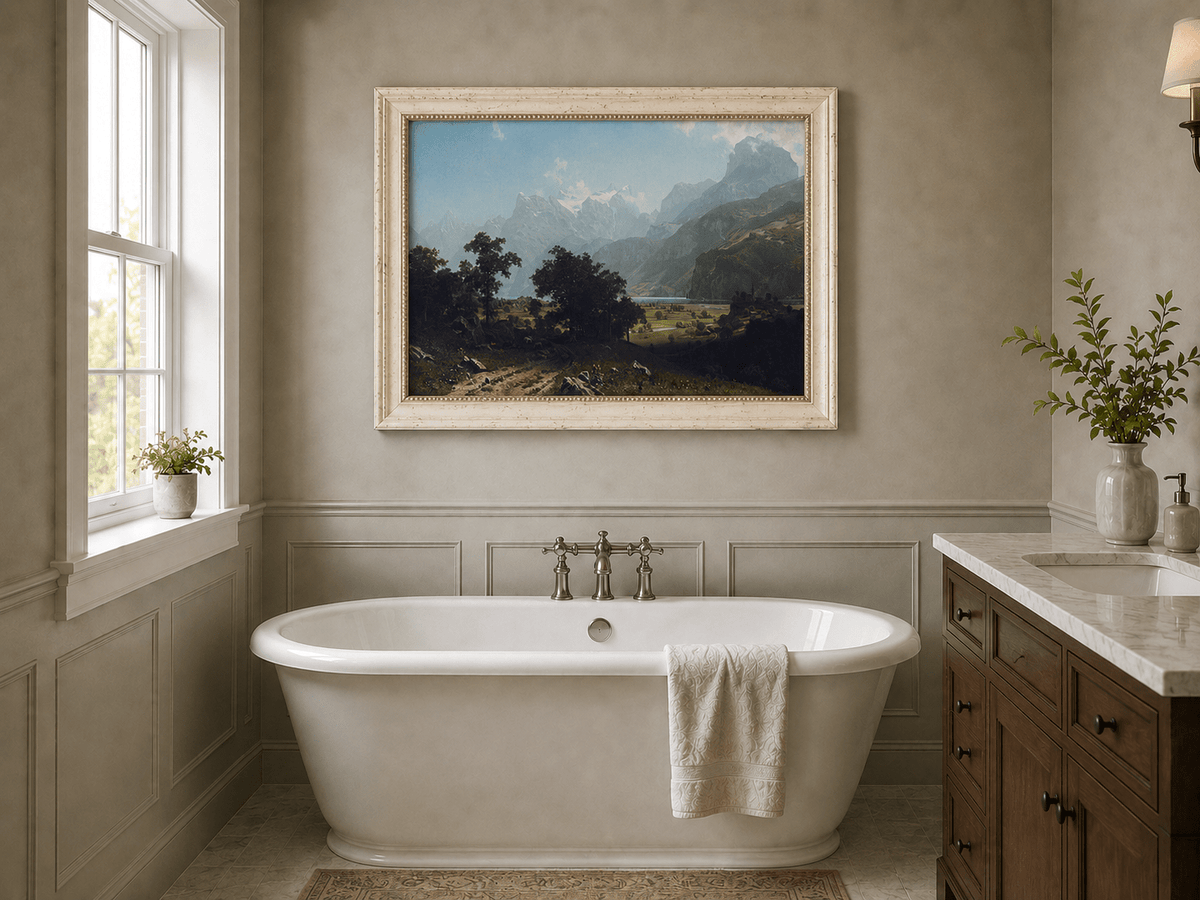 Framed hand-painted alpine valley oil painting with a lake and layered mountain peaks displayed above a freestanding bathtub.