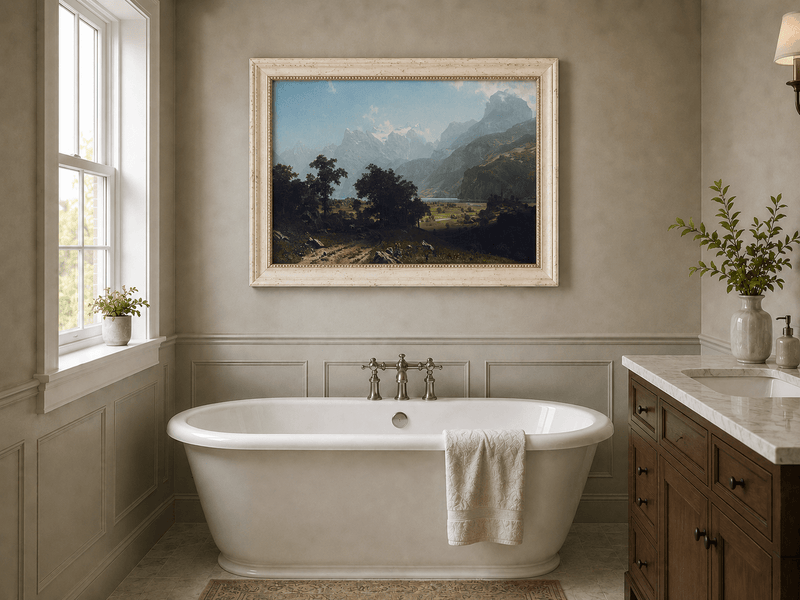 Framed hand-painted alpine valley oil painting with a lake and layered mountain peaks displayed above a freestanding bathtub.