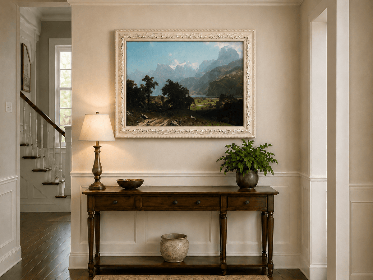 Framed hand-painted alpine valley oil painting with a lake and layered mountain peaks displayed above an entryway console table.