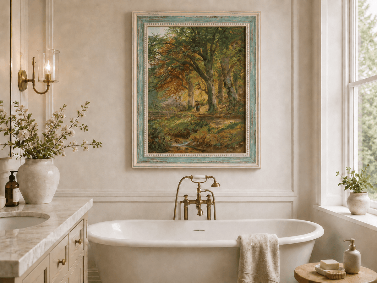 Framed hand-painted autumn forest oil painting with a leaf-covered path beside a stream displayed above a freestanding bathtub.