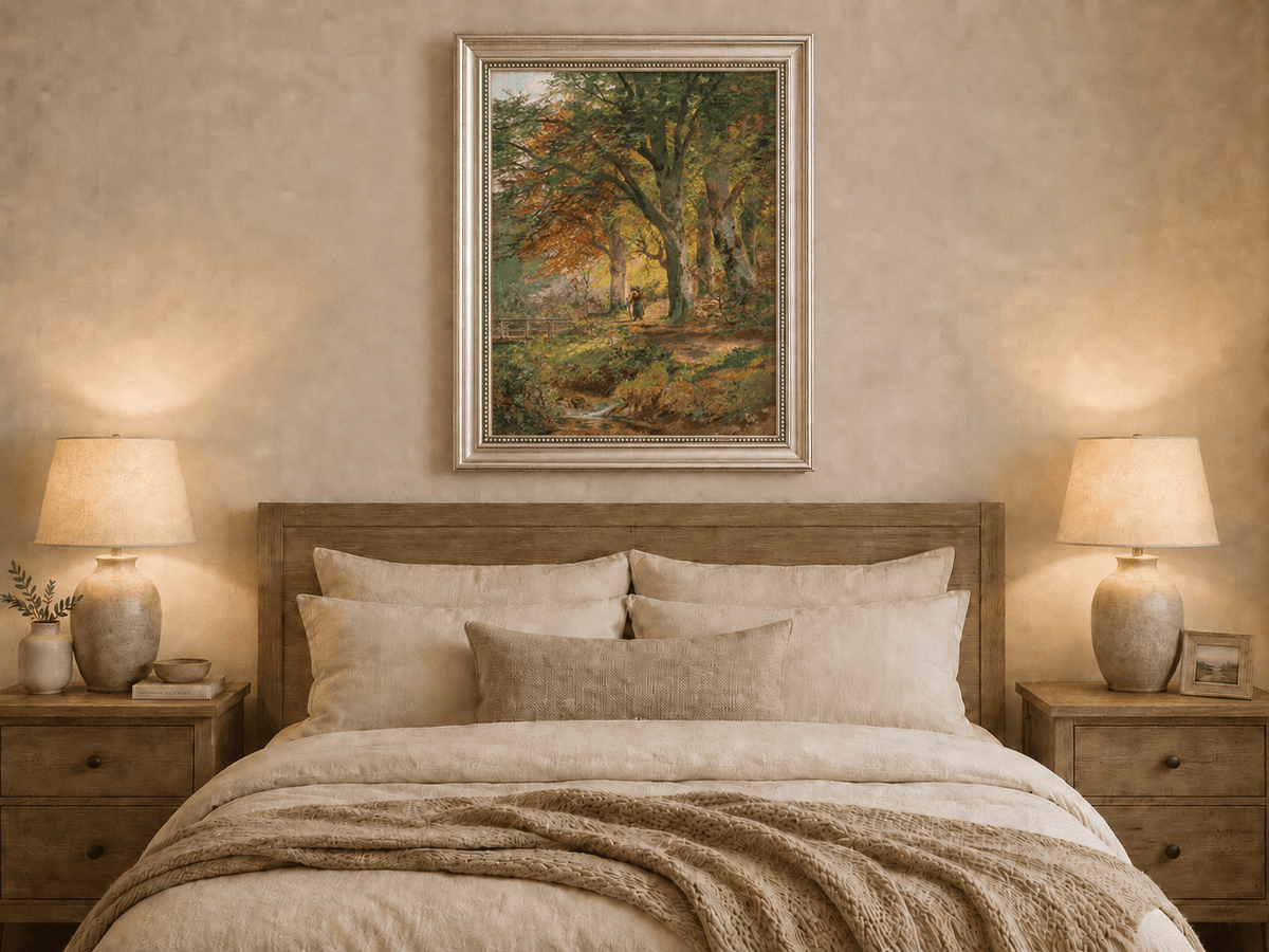 Framed hand-painted autumn forest oil painting with a leaf-covered path beside a stream displayed above a wooden bed in a neutral bedroom.