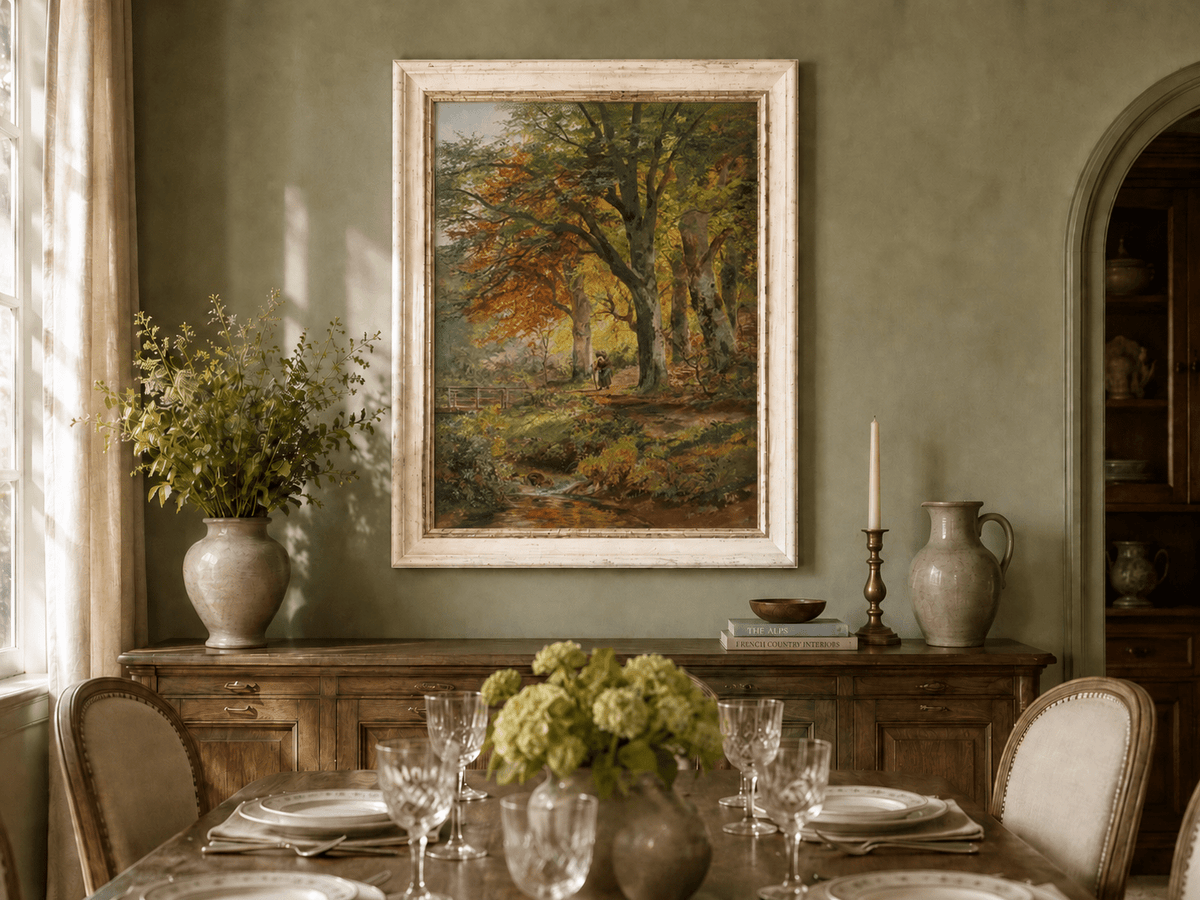 Framed hand-painted autumn forest oil painting with a leaf-covered path beside a stream displayed above a formal dining table.