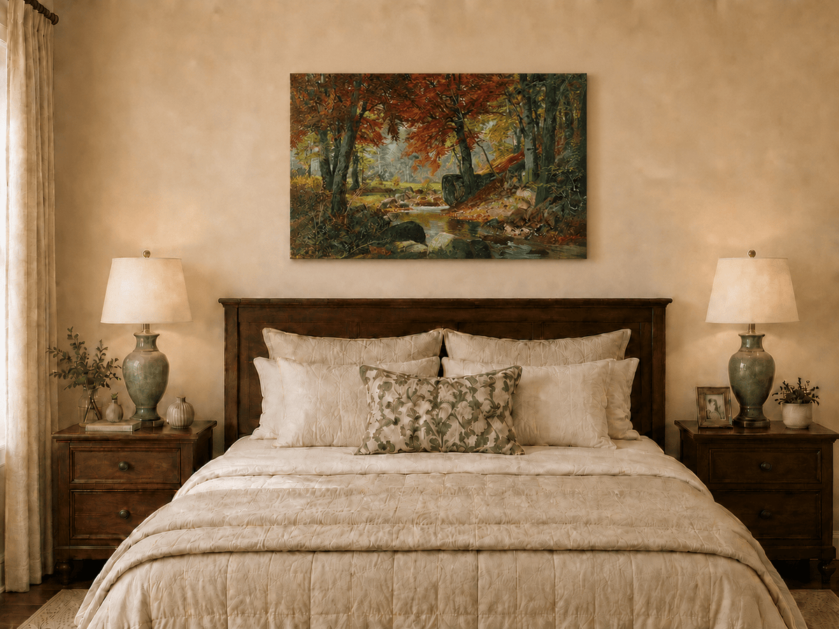 Unframed hand-painted autumn forest stream oil painting flowing around mossy boulders displayed above a wooden bed in a neutral bedroom.