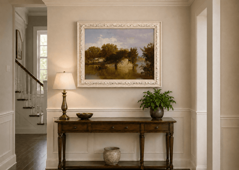 Framed hand-painted autumn river oil painting with golden trees, a rocky bank and reflections displayed above an entryway console table.