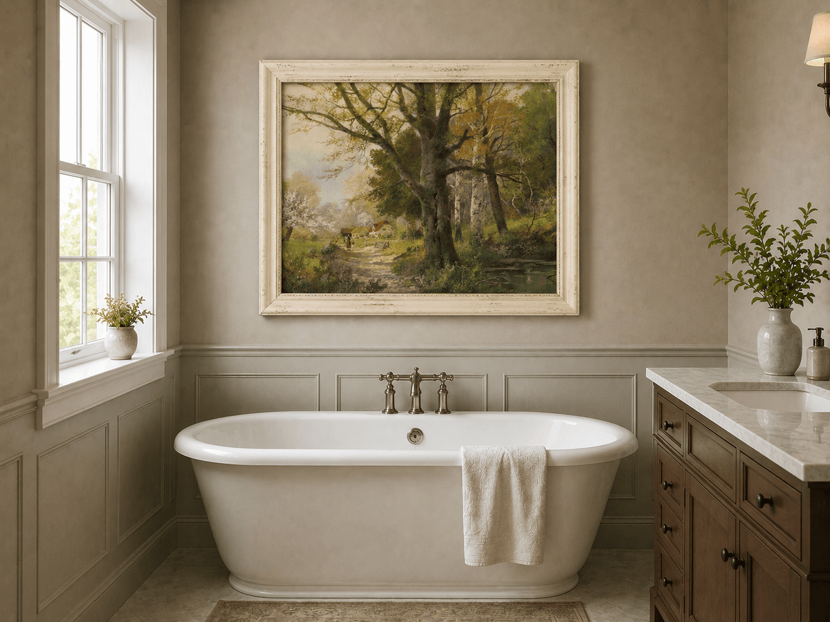 Framed hand-painted autumn woodland oil painting with a path leading to a country cottage displayed above a freestanding bathtub.