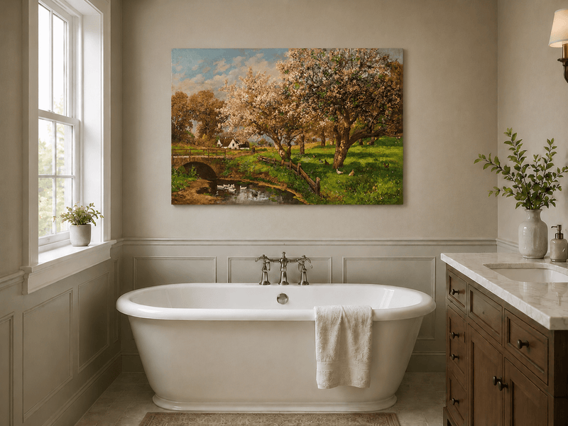 Unframed hand-painted blooming orchard oil painting with a stone bridge over a country stream displayed above a freestanding bathtub.