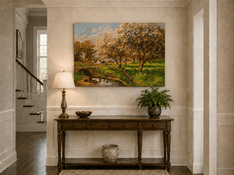 Unframed hand-painted blooming orchard oil painting with a stone bridge over a country stream displayed above an entryway console table.