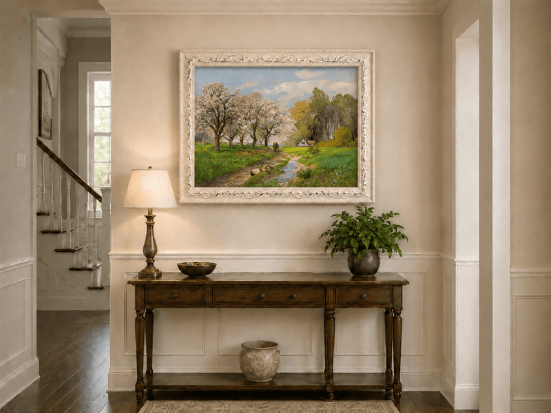 Framed hand-painted blooming orchard oil painting with a winding path leading to a cottage displayed above an entryway console table.