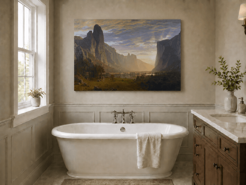 Unframed hand-painted cliffs and river oil painting illuminated by warm golden light displayed above a freestanding bathtub.