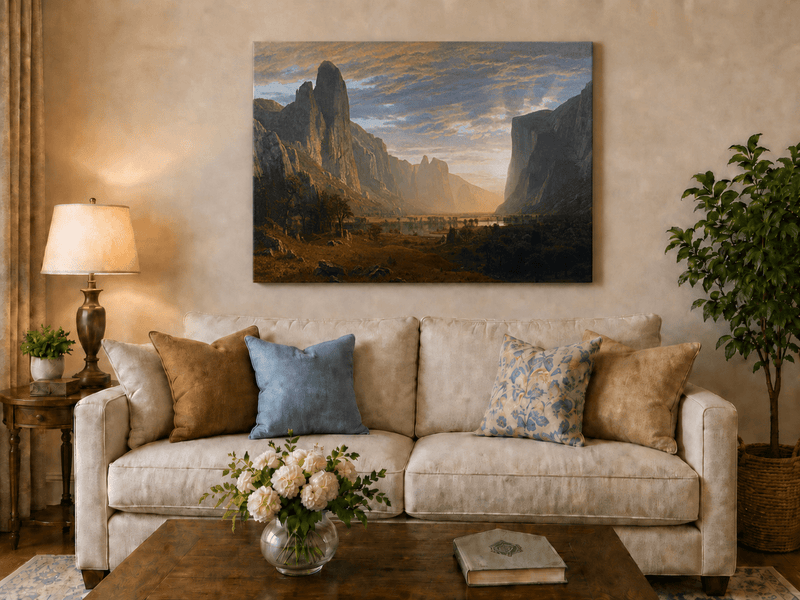 Unframed hand-painted cliffs and river oil painting illuminated by warm golden light displayed above a neutral living room sofa.