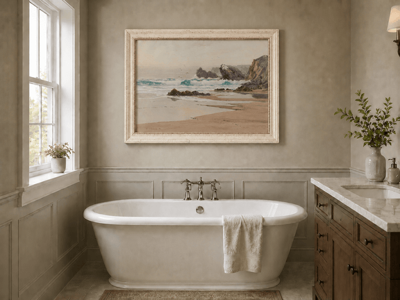 Framed hand-painted coastal beach oil painting with crashing waves and cliffside rocks displayed above a freestanding bathtub.
