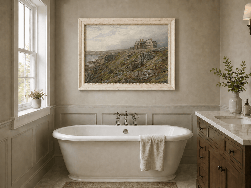 Framed hand-painted coastal oil painting with a cliff house, rocky slopes and seaside view displayed above a freestanding bathtub.