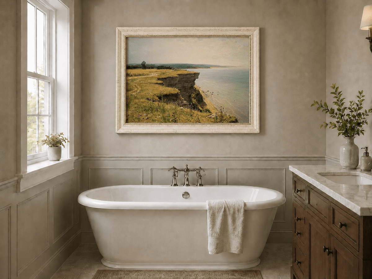 Framed hand-painted coastal landscape oil painting with a grassy cliff and expansive sea view displayed above a freestanding bathtub.