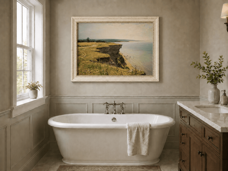 Framed hand-painted coastal landscape oil painting with a grassy cliff and expansive sea view displayed above a freestanding bathtub.