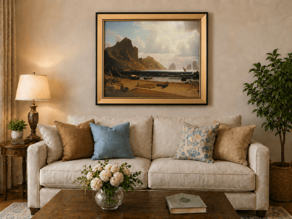Framed hand-painted coastal cliffs oil painting with fishing boats and figures on a rocky beach displayed above a neutral living room sofa.