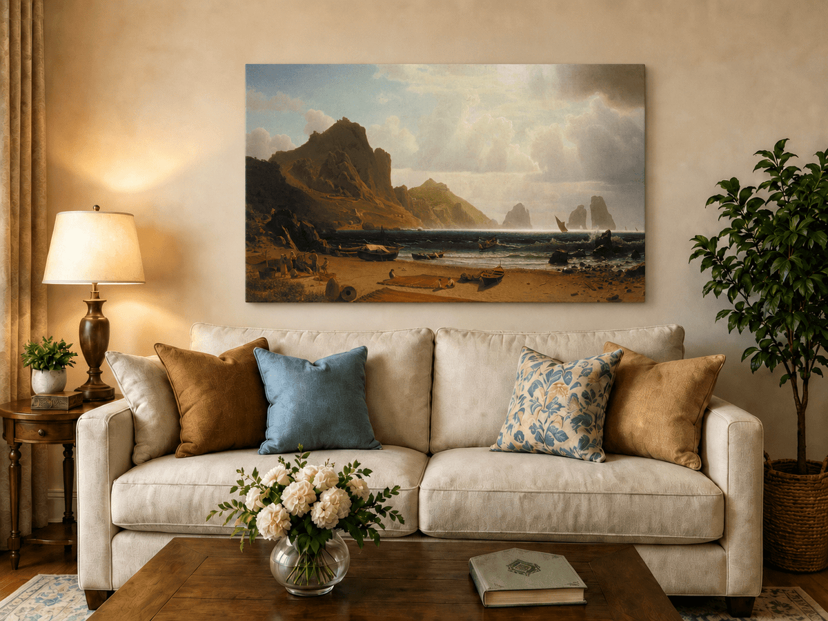 Unframed hand-painted coastal cliffs oil painting with fishing boats and figures on a rocky beach displayed above a neutral living room sofa.