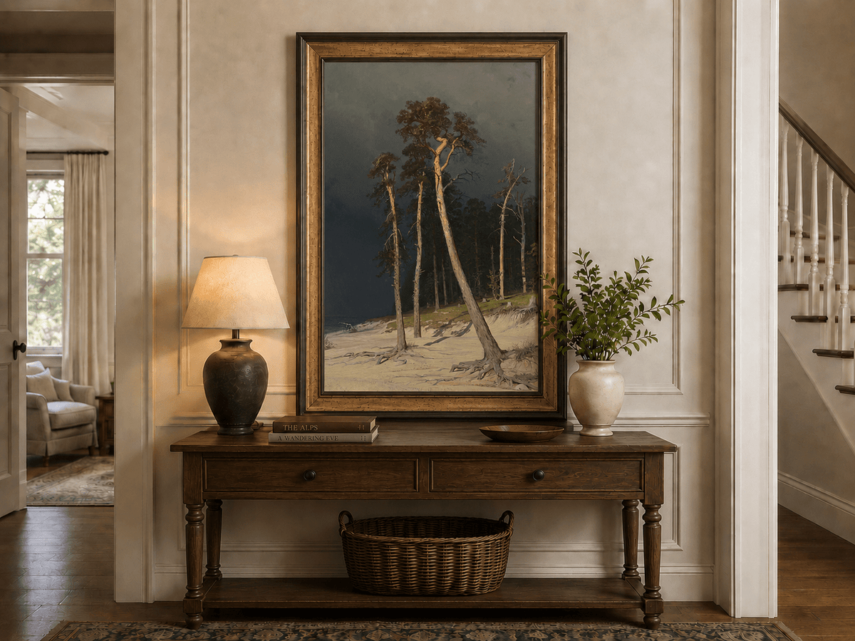 Framed hand-painted coastal forest oil painting with tall pines on a sandy shore displayed above an entryway console table.