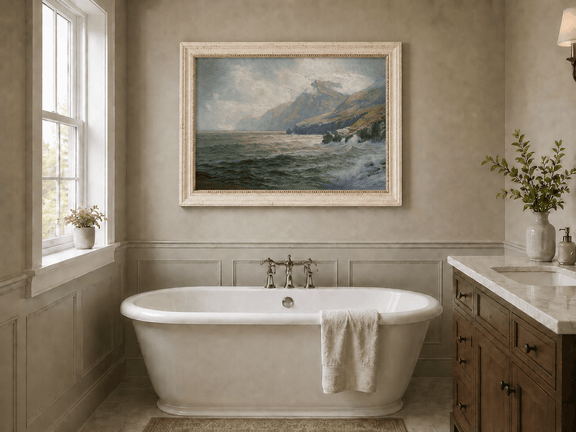 Framed hand-painted coastal mountain oil painting with waves breaking on a rocky shore displayed above a freestanding bathtub.