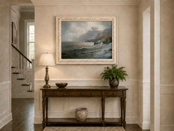 Framed hand-painted coastal mountain oil painting with waves breaking on a rocky shore displayed above an entryway console table.