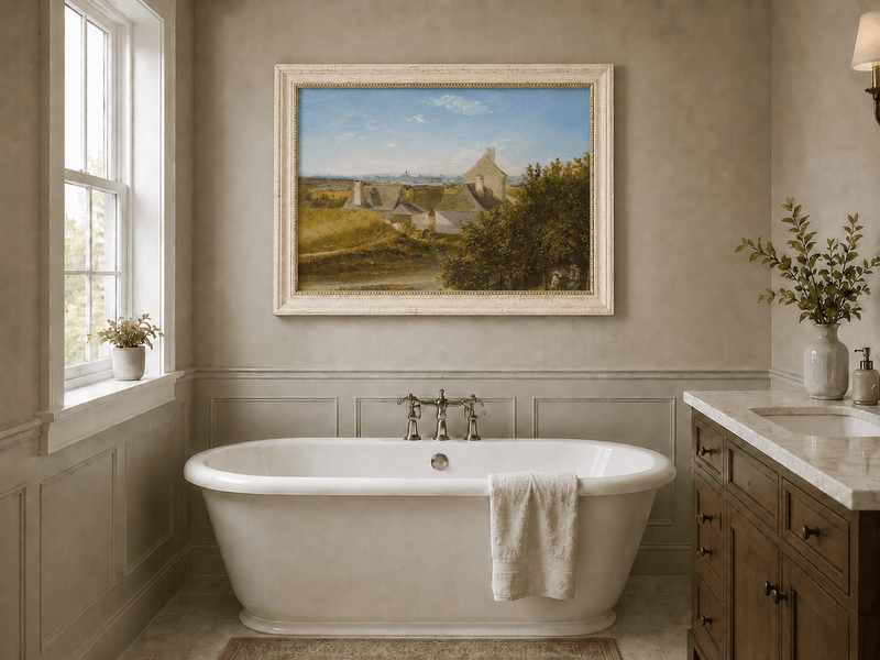Framed hand-painted country houses oil painting with a winding road and distant city view displayed above a freestanding bathtub.