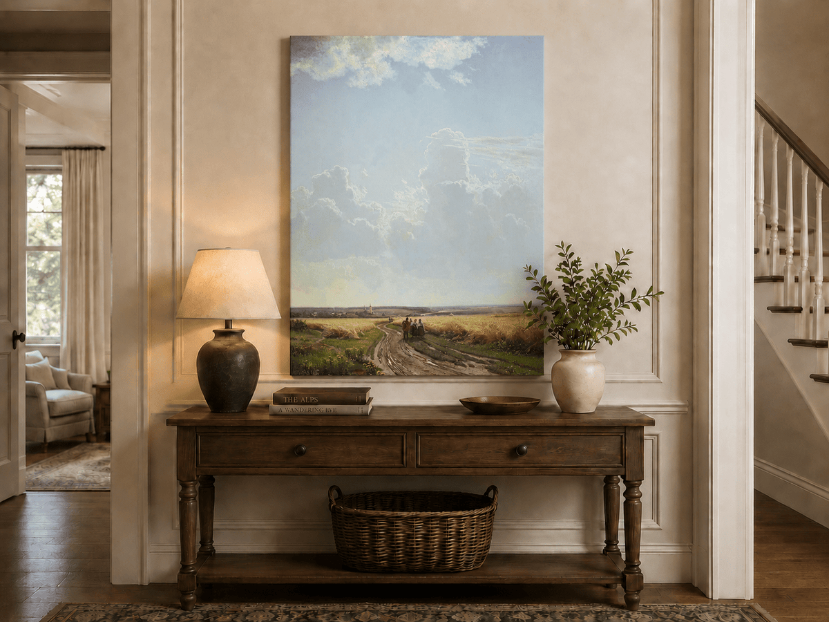 Unframed hand-painted countryside oil painting with a road through wheat fields beneath broad clouds displayed above an entryway console table.