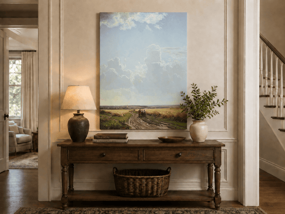 Unframed hand-painted countryside oil painting with a road through wheat fields beneath broad clouds displayed above an entryway console table.