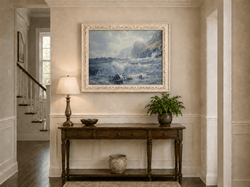 Framed hand-painted seascape oil painting with crashing waves along a rocky coastal shore displayed above an entryway console table.