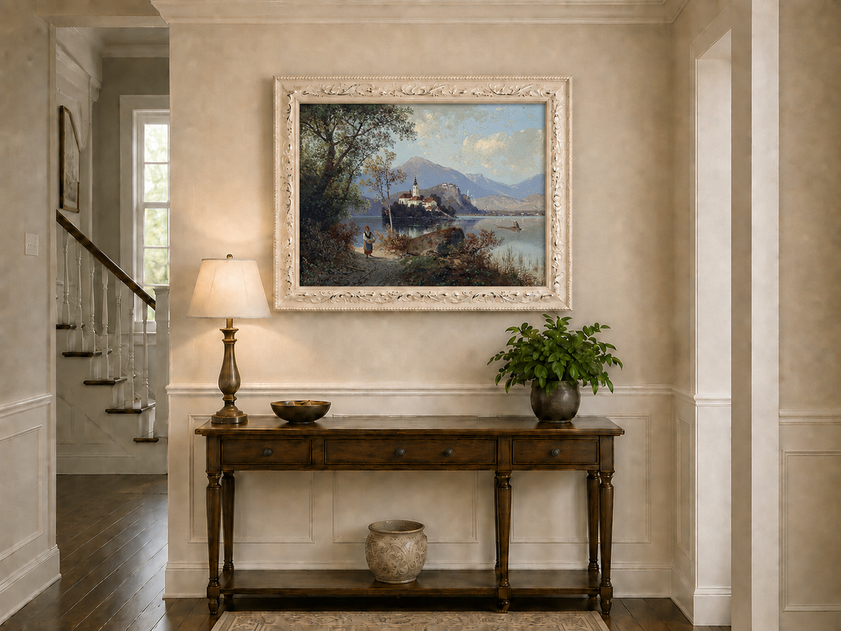 Hand-painted European lakeside village landscape oil painting displayed above a console table in a hallway interior.