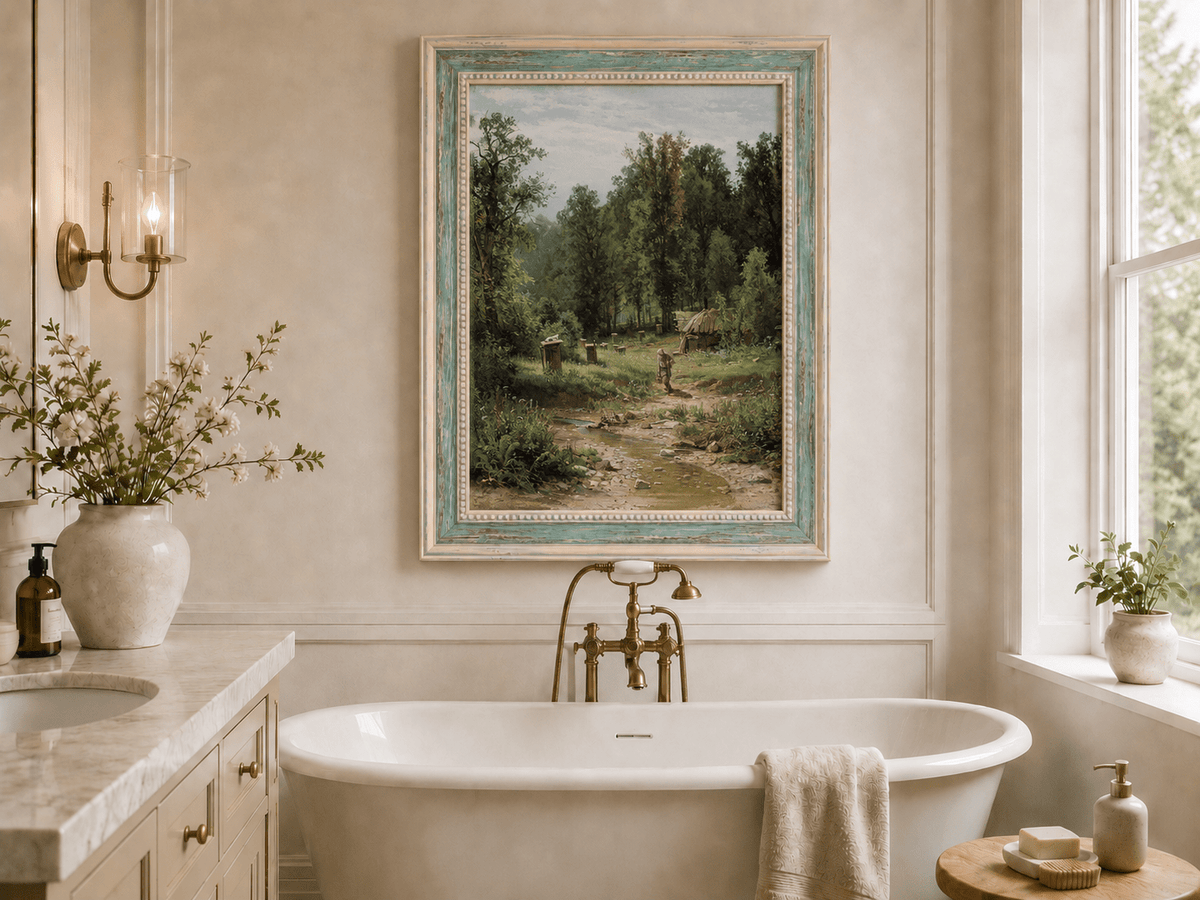 Framed hand-painted forest cottage oil painting with a stream, path and walking figure displayed above a freestanding bathtub.