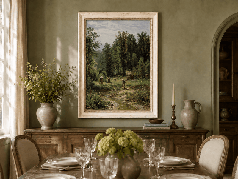 Framed hand-painted forest cottage oil painting with a stream, path and walking figure displayed above a formal dining table.