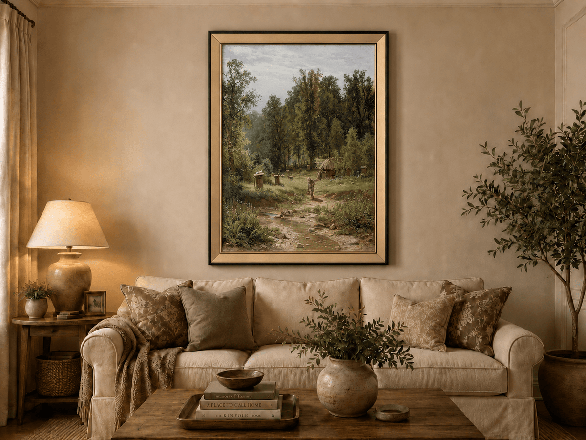 Framed hand-painted forest cottage oil painting with a stream, path and walking figure displayed above a neutral living room sofa.