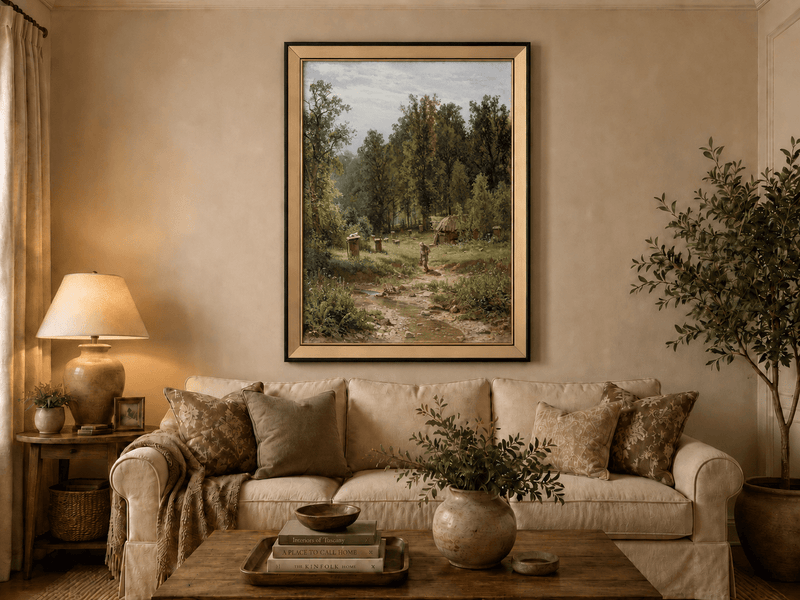 Framed hand-painted forest cottage oil painting with a stream, path and walking figure displayed above a neutral living room sofa.