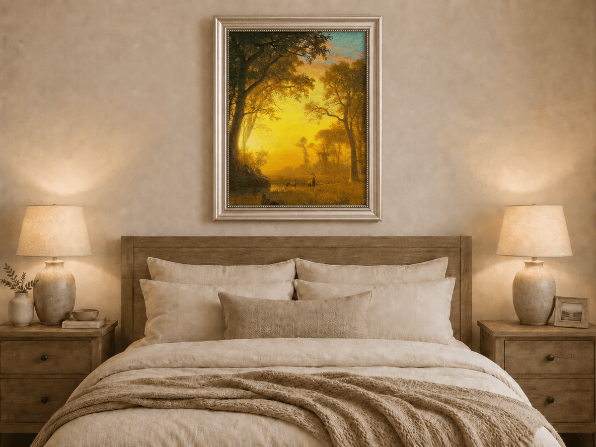 Framed hand-painted forest oil painting with deer by a stream at golden sunset displayed above a wooden bed in a neutral bedroom.