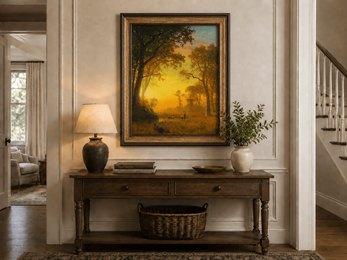 Framed hand-painted forest oil painting with deer by a stream at golden sunset displayed above an entryway console table.