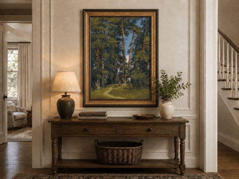 Framed hand-painted pine forest oil painting with a small elevated cabin among tall trees displayed above an entryway console table.
