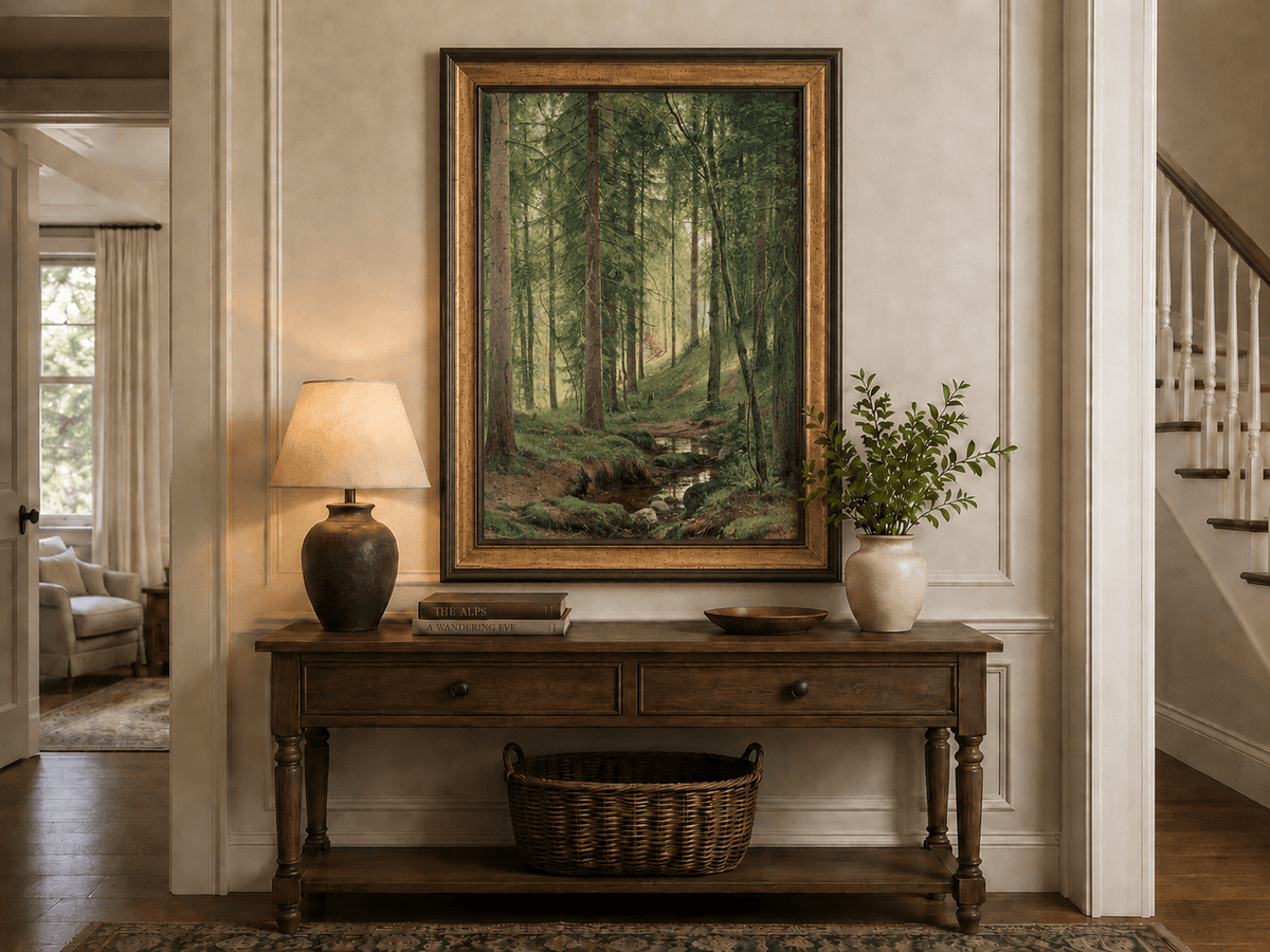 Framed hand-painted forest path oil painting with a quiet stream and fallen woodland logs displayed above an entryway console table.