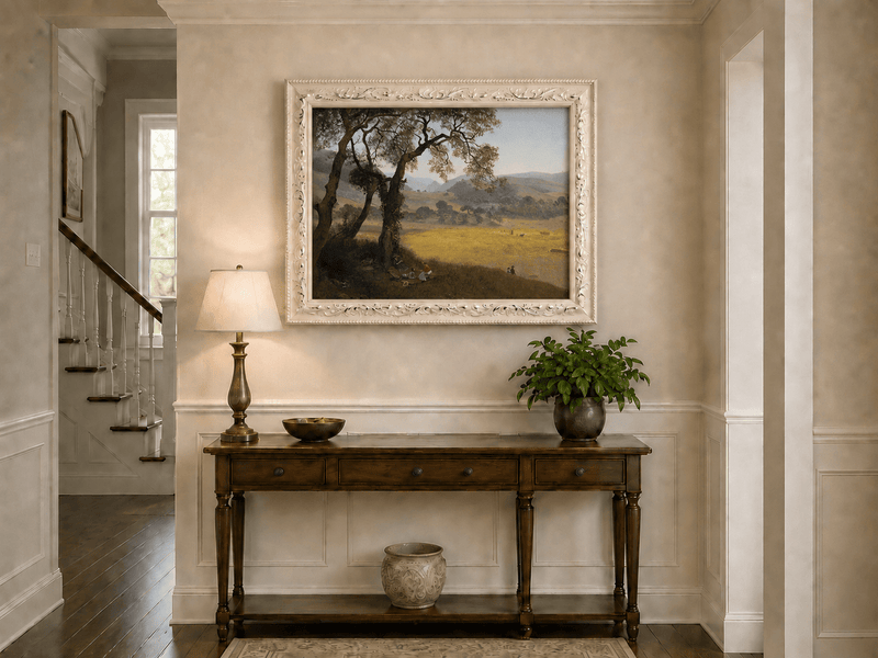 Framed hand-painted golden meadow oil painting with a picnic scene beneath a broad tree displayed above an entryway console table.