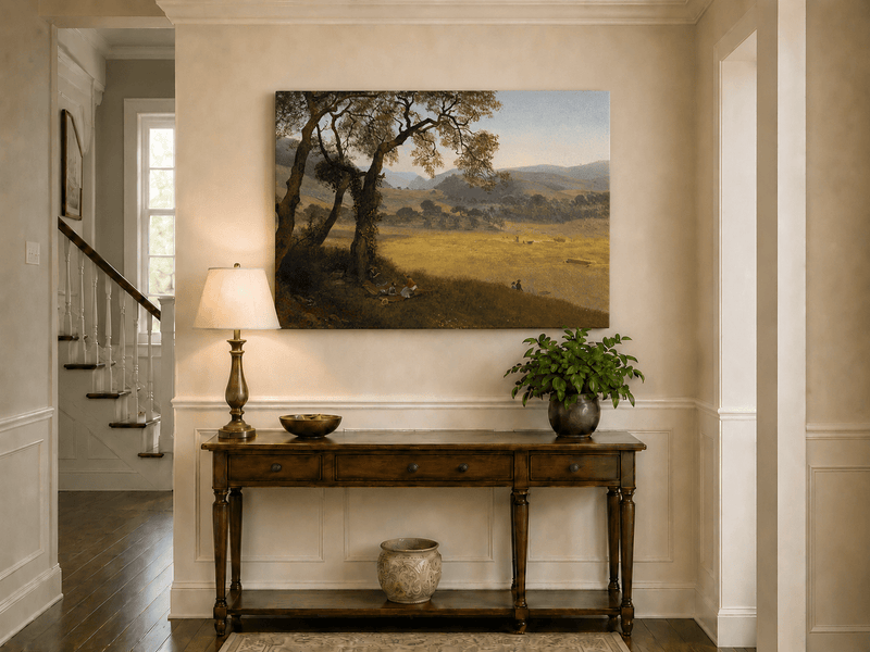 Unframed hand-painted golden meadow oil painting with a picnic scene beneath a broad tree displayed above an entryway console table.