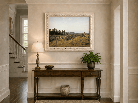 Framed hand-painted harvest field oil painting with haystacks and distant farm workers displayed above an entryway console table.