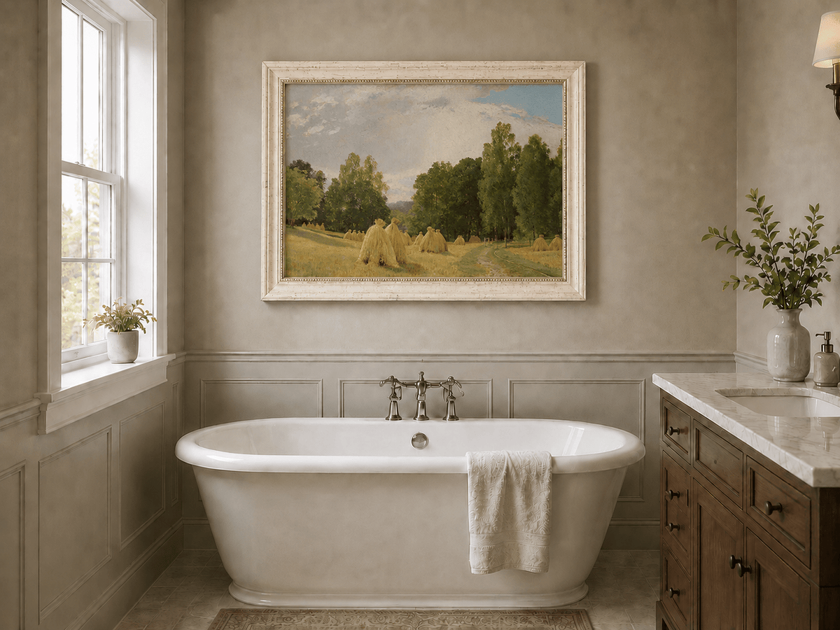 Framed hand-painted harvest field oil painting with haystacks and a tree-lined path displayed above a freestanding bathtub.