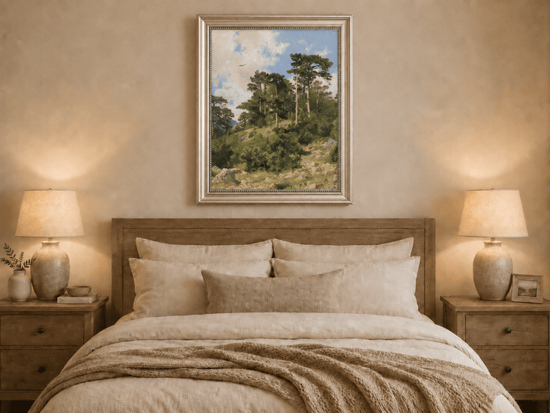 Framed hand-painted hillside oil painting with pine trees, rocks and open sky displayed above a wooden bed in a neutral bedroom.