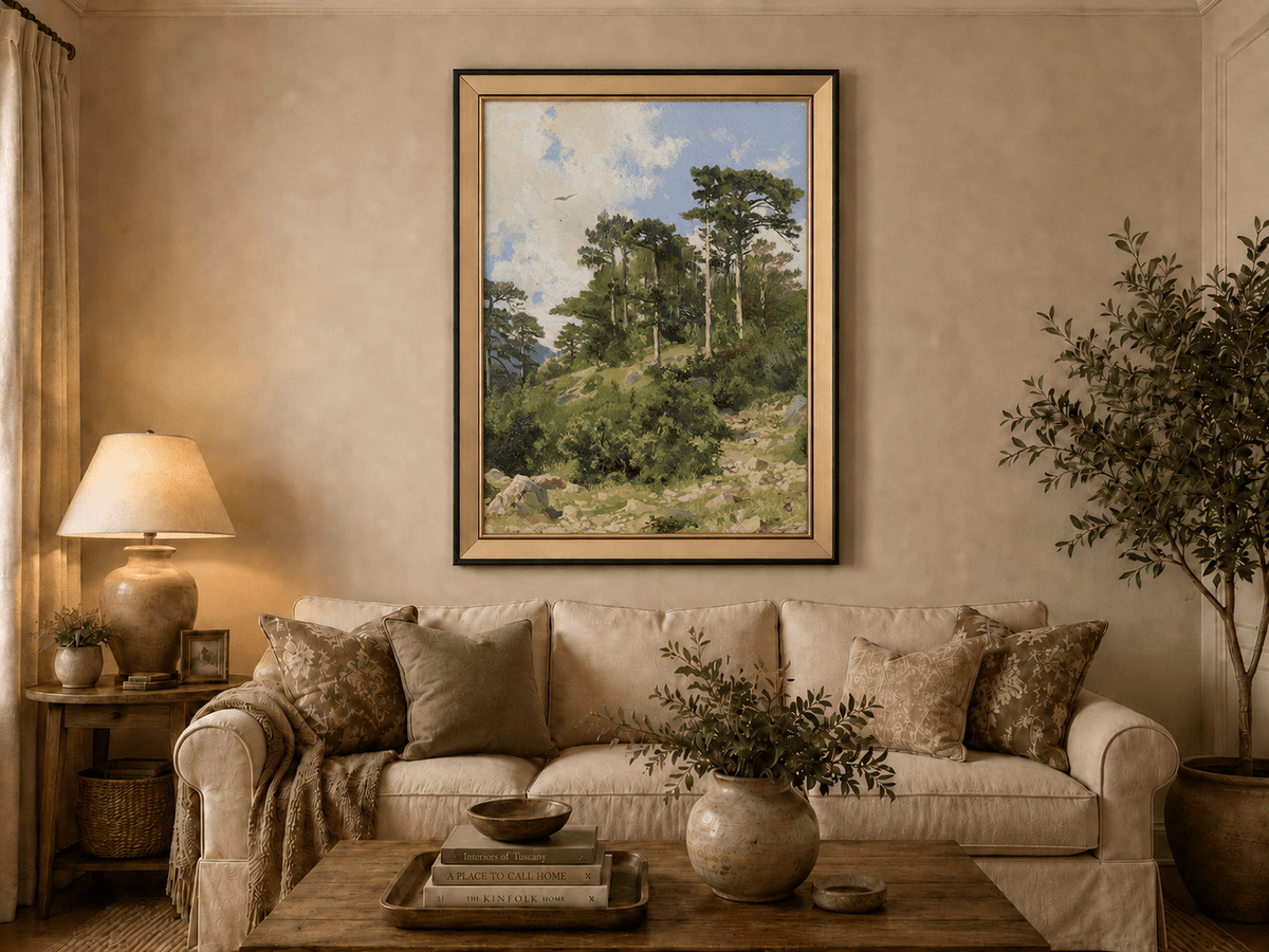 Framed hand-painted hillside oil painting with pine trees, rocks and open sky displayed above a neutral living room sofa.