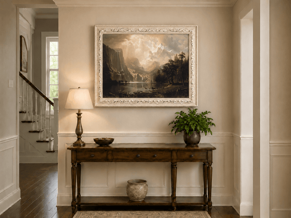 Framed hand-painted mountain stream oil painting with dramatic holy light breaking through clouds displayed above an entryway console table.