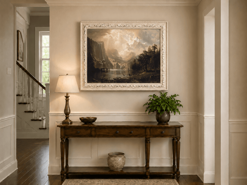 Framed hand-painted mountain stream oil painting with dramatic holy light breaking through clouds displayed above an entryway console table.