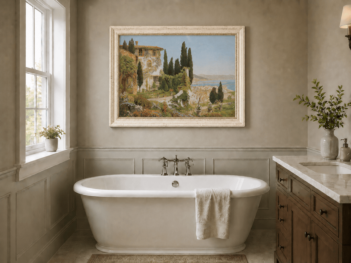 Framed hand-painted Italian garden oil painting with cypress trees overlooking the sea displayed above a freestanding bathtub.