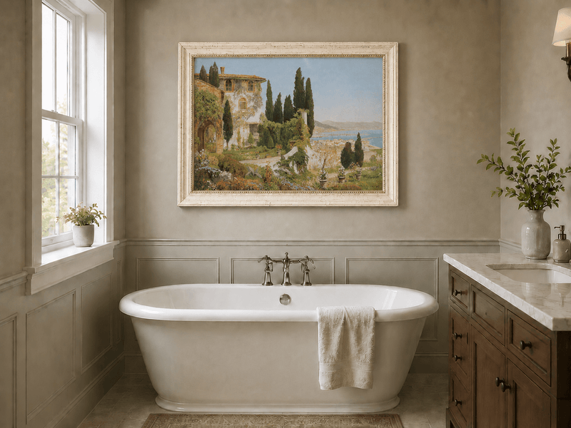 Framed hand-painted Italian garden oil painting with cypress trees overlooking the sea displayed above a freestanding bathtub.